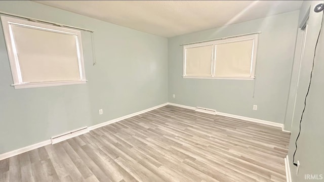 spare room featuring a baseboard radiator and light hardwood / wood-style flooring