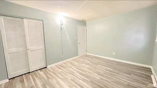 unfurnished bedroom featuring light hardwood / wood-style flooring and a closet