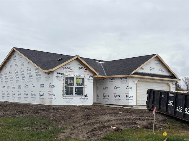 unfinished property with an attached garage and a shingled roof