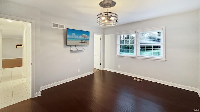 unfurnished room with an inviting chandelier and hardwood / wood-style flooring