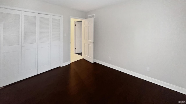 unfurnished bedroom with dark hardwood / wood-style flooring and a closet