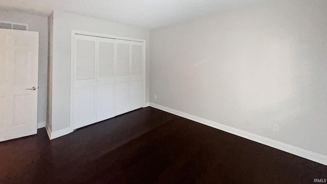 unfurnished bedroom with dark wood-type flooring and a closet