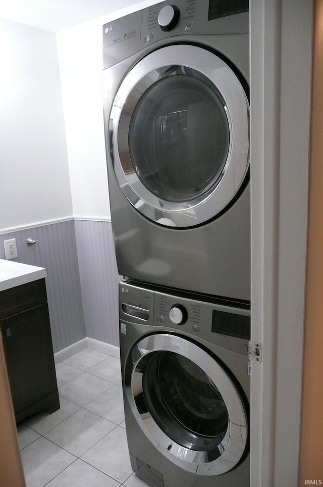 laundry room featuring stacked washer / dryer and light tile patterned flooring