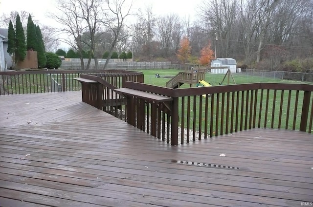 wooden deck with a playground and a lawn