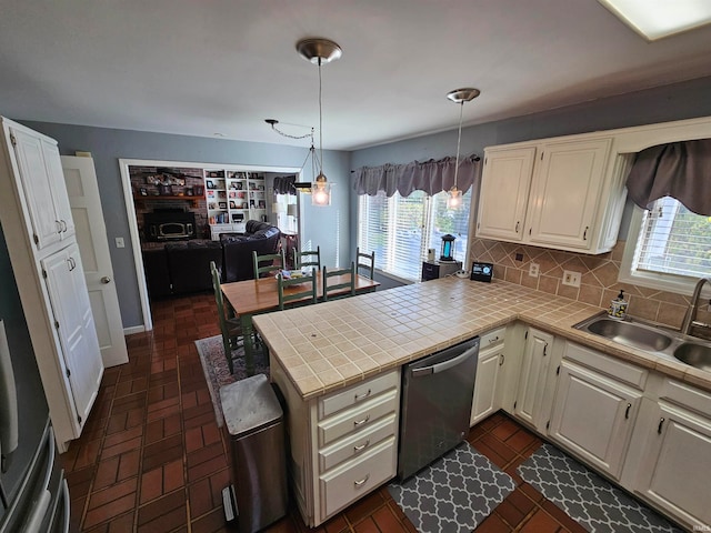 kitchen featuring stainless steel dishwasher, kitchen peninsula, sink, and a wealth of natural light