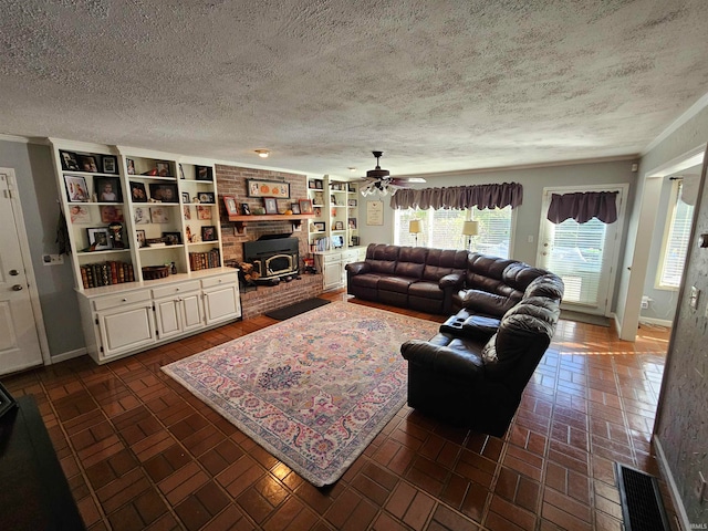 living room featuring a wood stove, ceiling fan, crown molding, and a textured ceiling