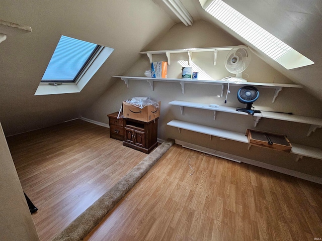 additional living space featuring light hardwood / wood-style floors and vaulted ceiling with skylight