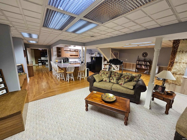 living room with hardwood / wood-style floors, a paneled ceiling, and ornate columns