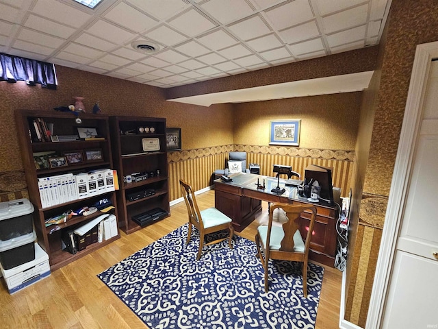 home office with a drop ceiling and wood-type flooring