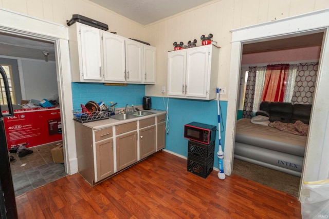 kitchen with decorative backsplash, dark hardwood / wood-style flooring, crown molding, sink, and white cabinets