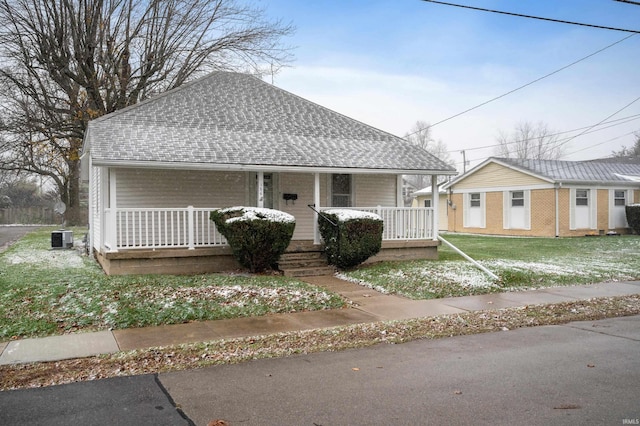 view of front of home featuring central AC, a front lawn, covered porch, and an outdoor structure