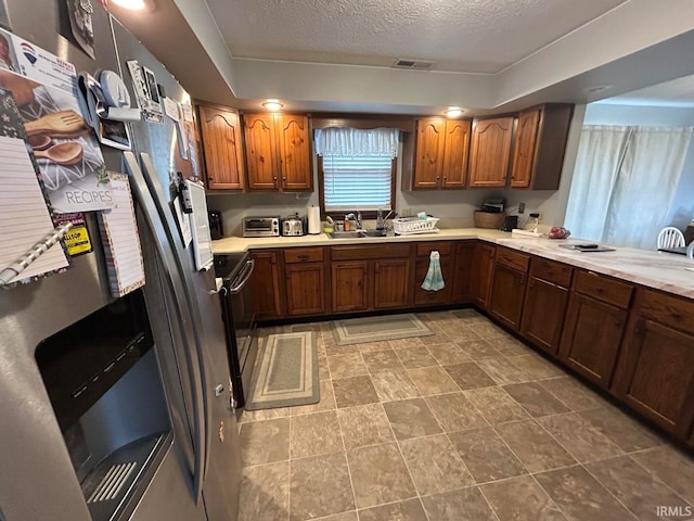 kitchen with stainless steel fridge with ice dispenser, a textured ceiling, and sink