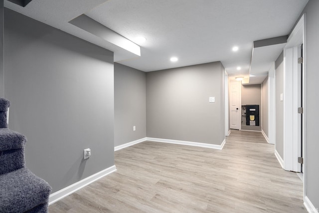 basement featuring light hardwood / wood-style floors and a textured ceiling