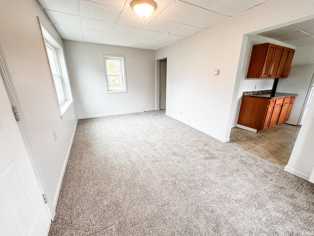 interior space featuring a paneled ceiling and light colored carpet