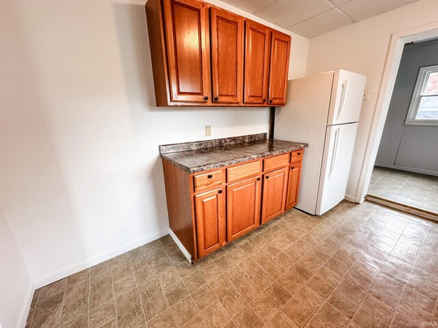 kitchen with a paneled ceiling and white fridge