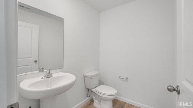 bathroom with hardwood / wood-style floors, toilet, and sink