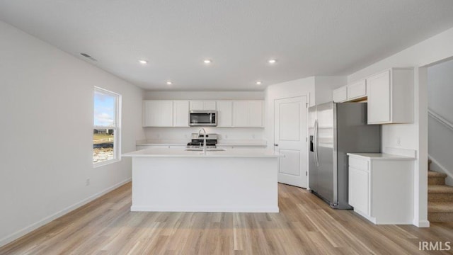 kitchen featuring a kitchen island with sink, sink, light hardwood / wood-style floors, white cabinetry, and stainless steel appliances