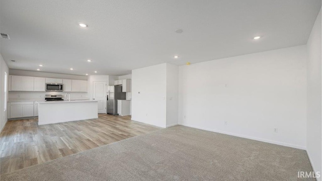 unfurnished living room with sink and light colored carpet