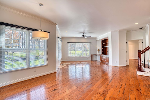 unfurnished living room featuring hardwood / wood-style flooring, ceiling fan, and crown molding