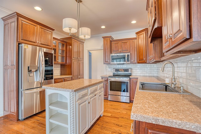 kitchen featuring appliances with stainless steel finishes, ornamental molding, sink, light hardwood / wood-style flooring, and a kitchen island