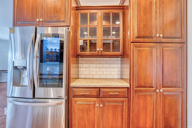 kitchen featuring light stone countertops, stainless steel fridge with ice dispenser, backsplash, and hardwood / wood-style flooring