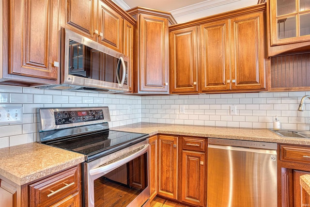 kitchen featuring backsplash, ornamental molding, stainless steel appliances, sink, and light hardwood / wood-style flooring