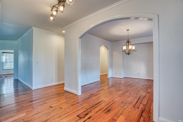 empty room with light wood-type flooring, an inviting chandelier, and ornamental molding