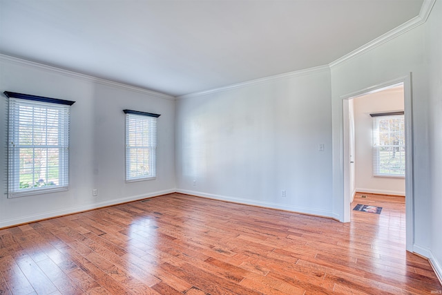 empty room featuring light wood-type flooring and crown molding