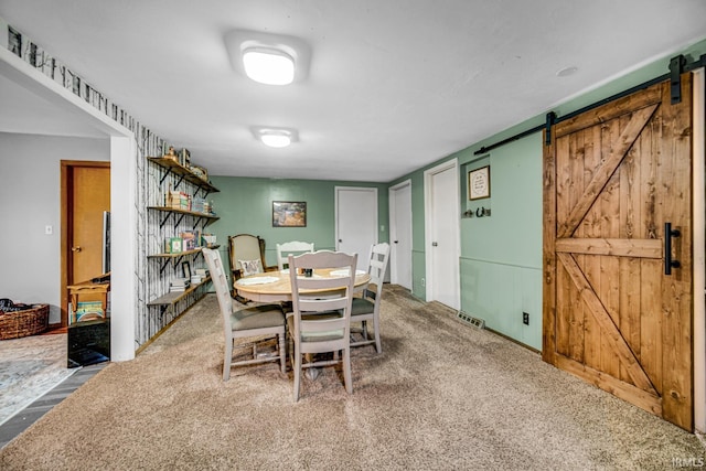 carpeted dining space featuring a barn door