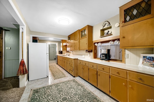 kitchen featuring decorative backsplash, white refrigerator, and sink