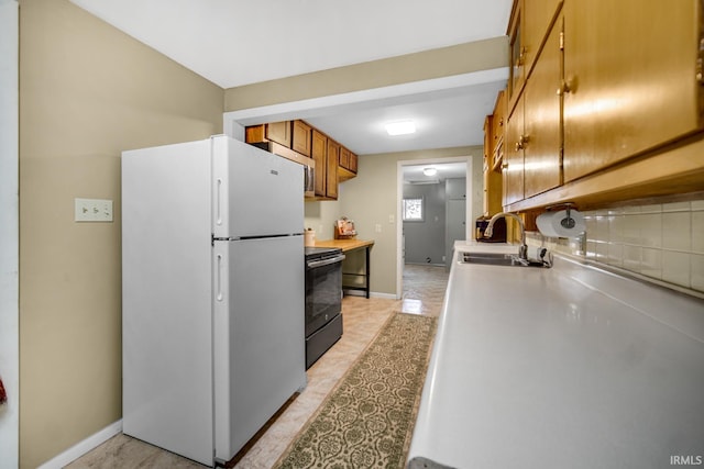 kitchen with black electric range, white refrigerator, backsplash, and sink