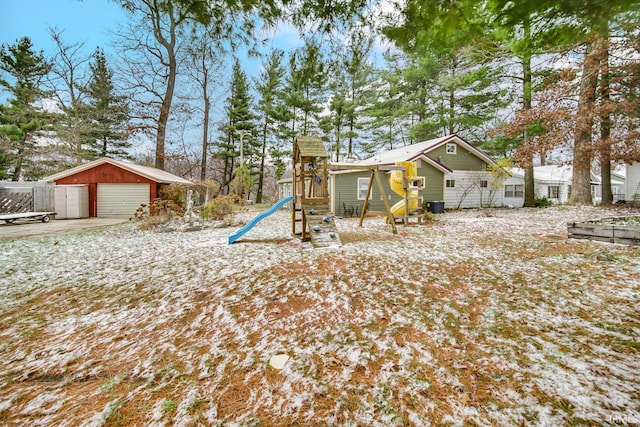 yard covered in snow featuring a playground, an outdoor structure, and a garage