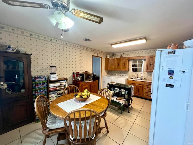 tiled dining space featuring separate washer and dryer, ceiling fan, and sink