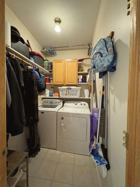 laundry area featuring cabinets, independent washer and dryer, a textured ceiling, and light tile patterned floors