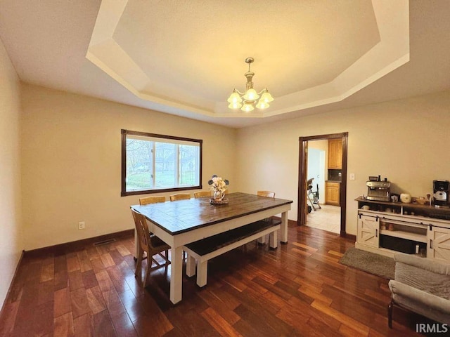 dining room featuring a chandelier, dark hardwood / wood-style flooring, and a raised ceiling