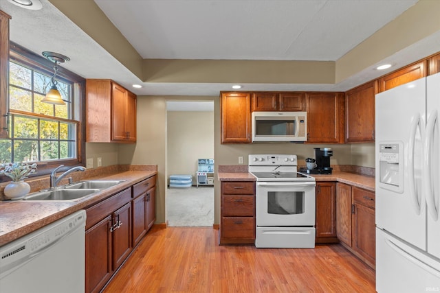 kitchen with sink, decorative light fixtures, white appliances, and light hardwood / wood-style floors