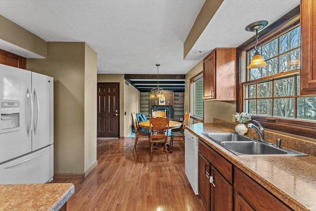 kitchen with sink, decorative light fixtures, white appliances, and light hardwood / wood-style flooring