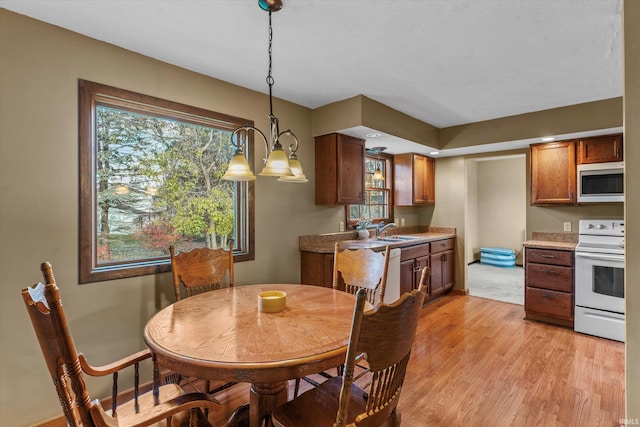 dining room featuring a wealth of natural light, sink, light hardwood / wood-style floors, and an inviting chandelier