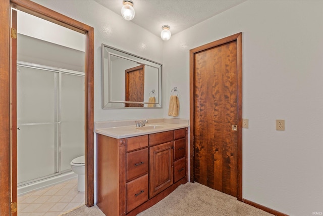 bathroom featuring a textured ceiling, vanity, toilet, and a shower with shower door