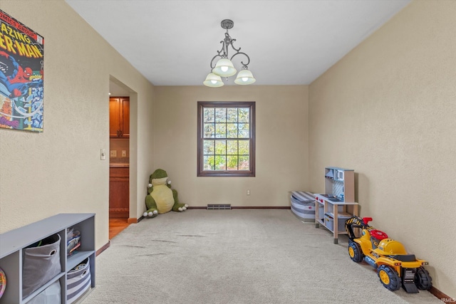 game room featuring light carpet and a chandelier