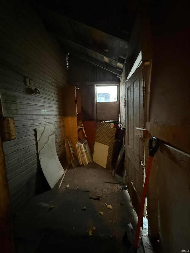 miscellaneous room featuring lofted ceiling and wood walls