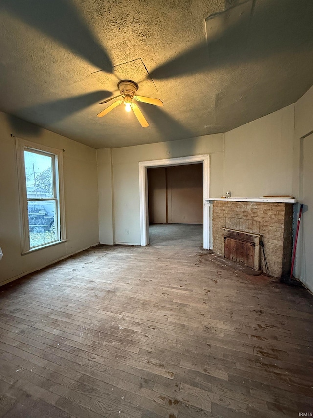 unfurnished living room featuring hardwood / wood-style floors, ceiling fan, and a textured ceiling