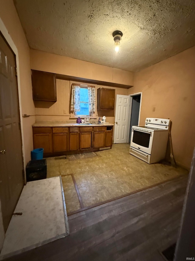 kitchen with electric range, light hardwood / wood-style flooring, and a textured ceiling