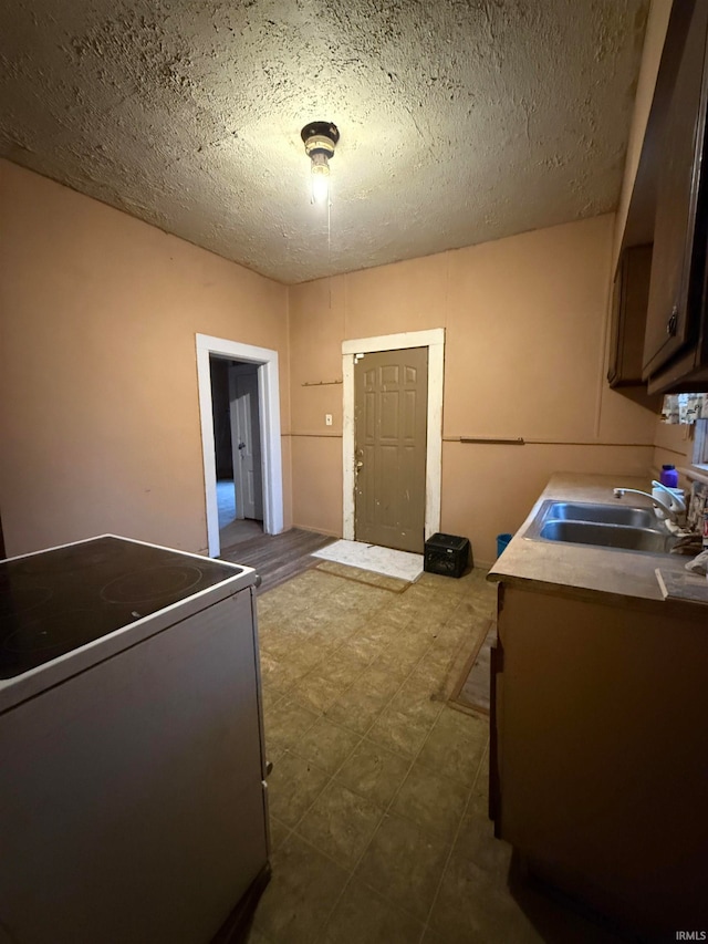 kitchen with a textured ceiling, stove, and sink