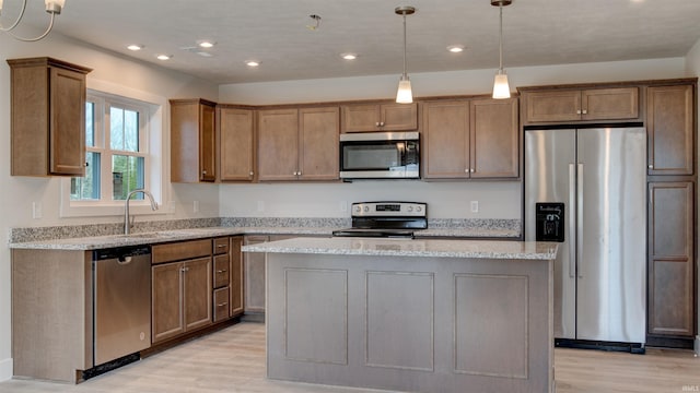 kitchen with light hardwood / wood-style flooring, appliances with stainless steel finishes, sink, and a kitchen island