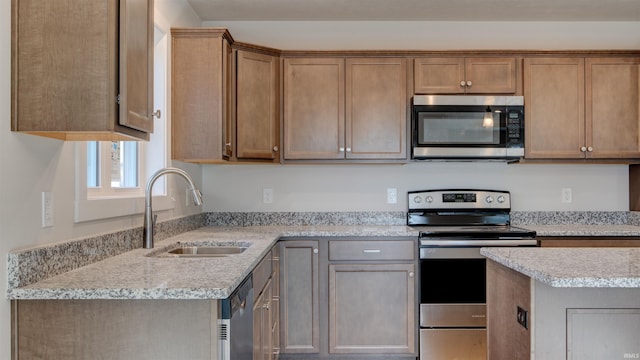 kitchen featuring appliances with stainless steel finishes, sink, and light stone counters