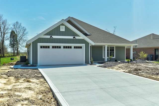 view of front of house with central air condition unit, driveway, roof with shingles, and a garage