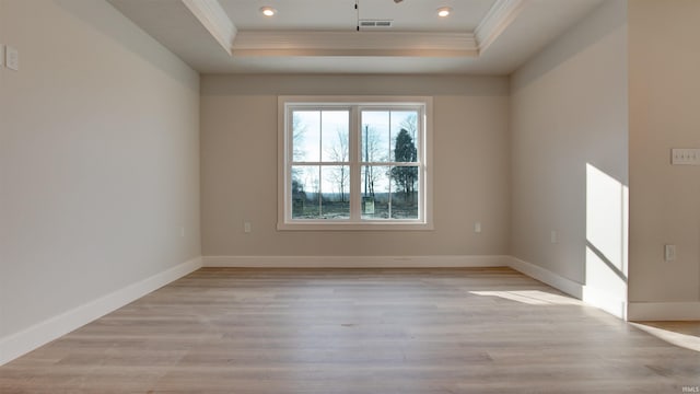 empty room featuring a raised ceiling and light wood-type flooring