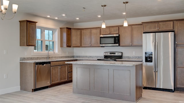 kitchen with pendant lighting, appliances with stainless steel finishes, a center island, and a notable chandelier