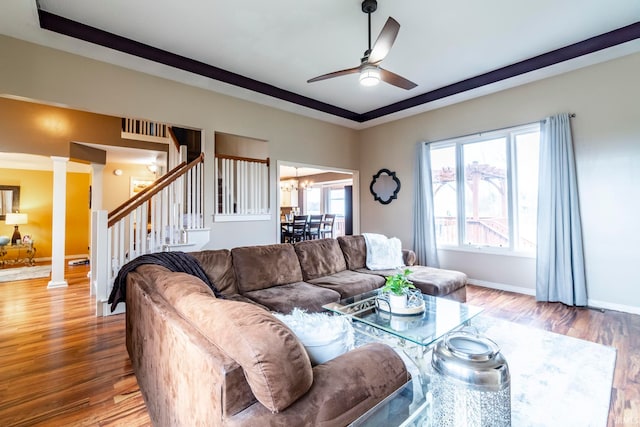 living room featuring ceiling fan with notable chandelier, light hardwood / wood-style flooring, and ornate columns